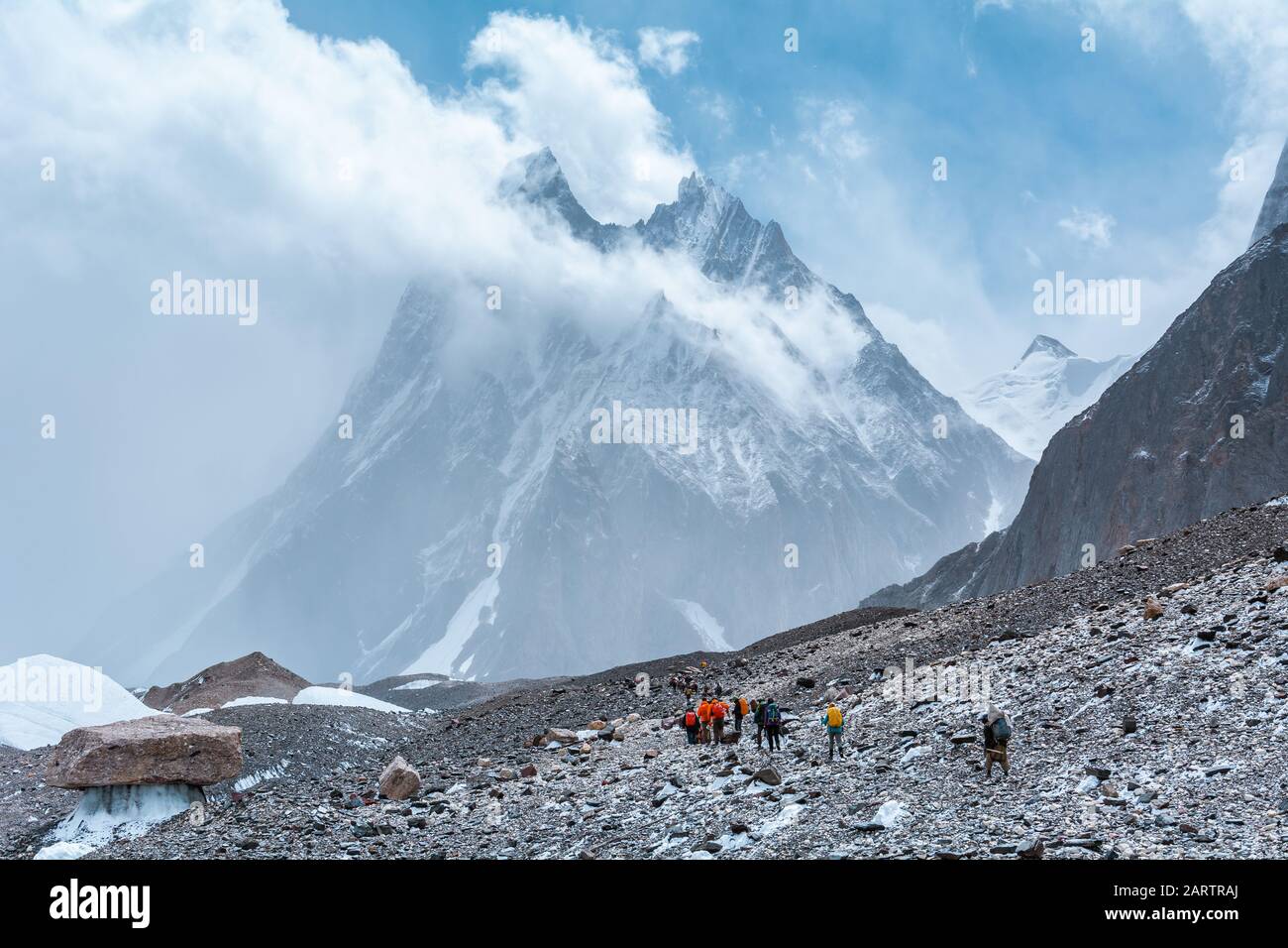 Trekkers walking to Concordia with Mitre Peak in the cloudy sky, Pakistan Stock Photo