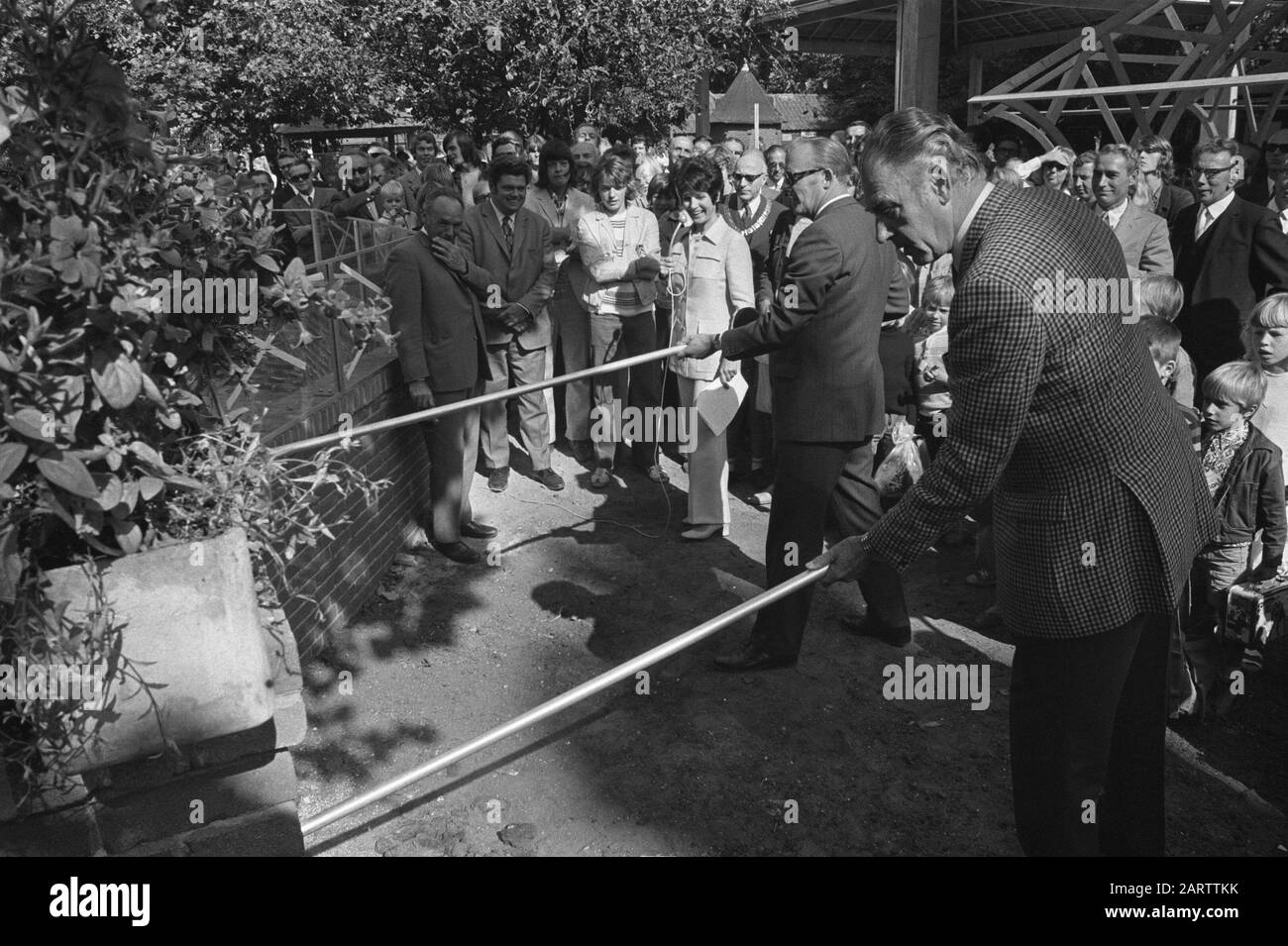 State Secretary Vonhoff mast stone in apprenticeship building site Artis in connection with 25 years Stichting Vakopleiding Bouwnijverheid Amsterdam, [two men open tubes with sticks under watchful eye van Vonhoff en Mies Bouwman] Date: 9 September 1971 Location: Amsterdam, Noord-Holland Keywords: Zoos, Stones Personname: Bouwman, Mies, Vonhoff, Henk Stock Photo