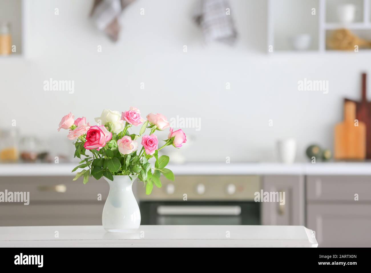 Beautiful rose flowers in vase on table in kitchen Stock Photo