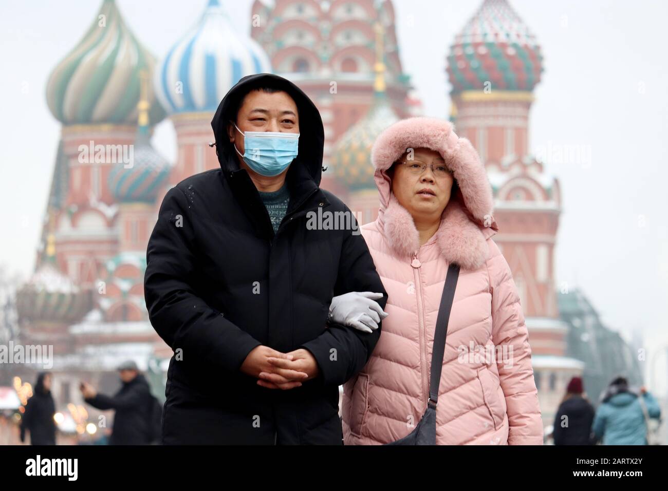 Chinese couple walking on a Red square on background of St Basil's Cathedral. Man in protective medical mask, prevention of coronavirus, asian tourist Stock Photo