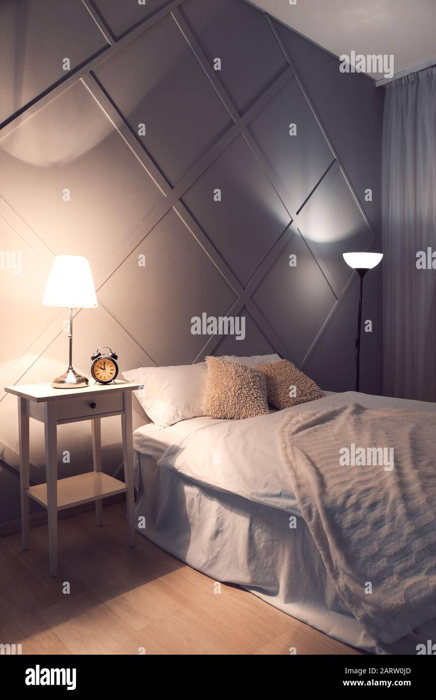 Big comfortable bed in interior of room at night Stock Photo Alamy