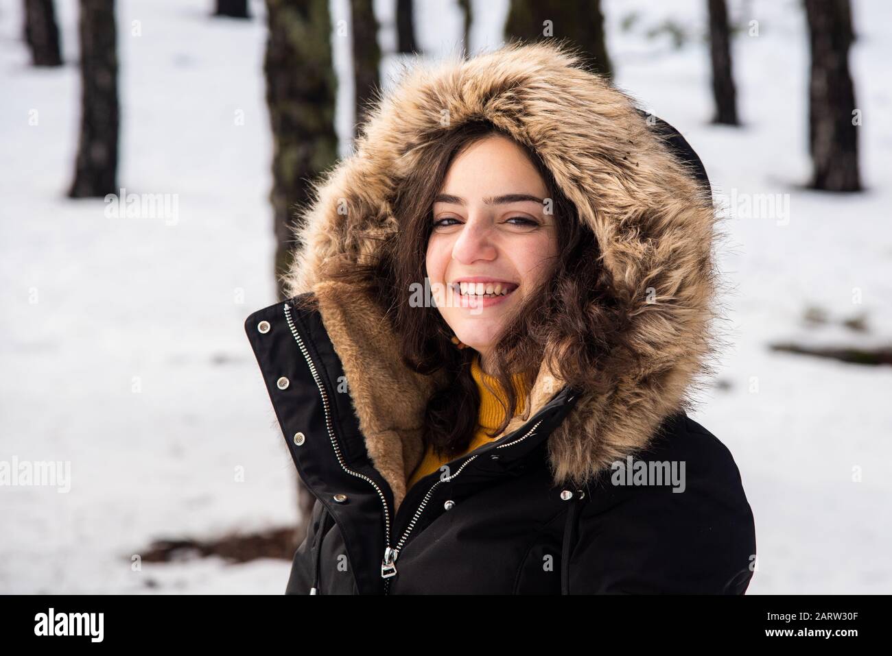 Portrait of a Young happy and beautiful teenage girl dressed in winter clothing standing at snow and smiling. Troodos mountains in Cyprus Stock Photo