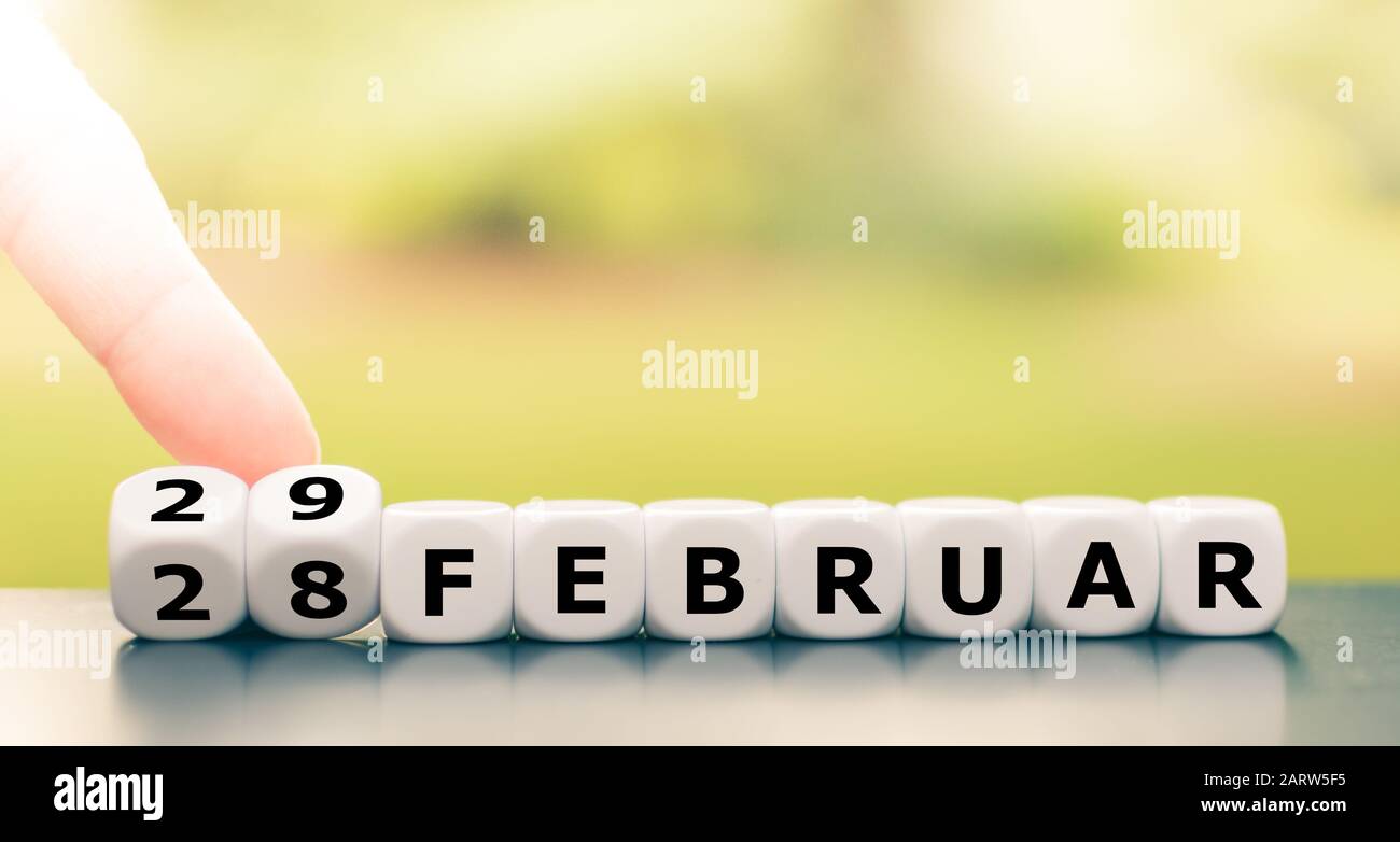 Hand turns dice and changes the date from 'February 28' to 'February 29' (28 and 29 Februar in German. Stock Photo