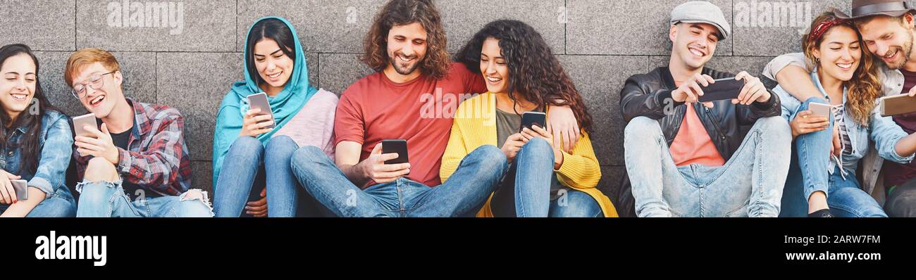 Group of friends using mobile smartphone outdoor - Trendy young people having fun with new technology apps for social media phone Stock Photo