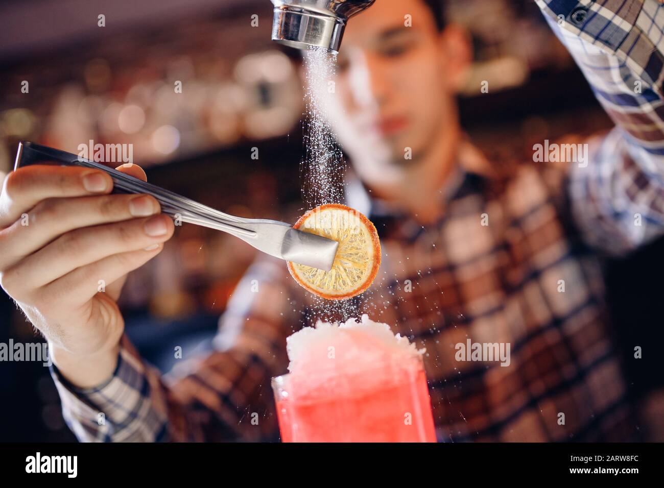 Barman mixes blue cocktail show with colorful alcoholic and with icing sugar orange bar counter Stock Photo