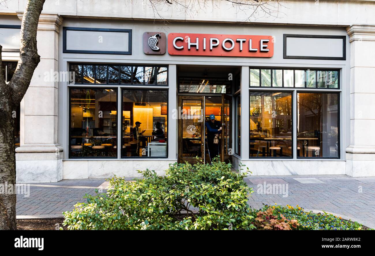 CHARLOTTE, NC, USA-26 JAN 2020: A Chipotle fast food restaurant in uptown Charlotte.  A man exits while two people sit inside. Stock Photo