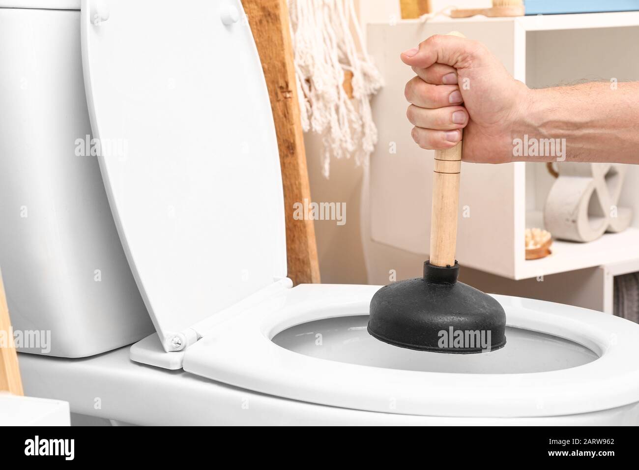 Man using plunger to unclog a toilet bowl Stock Photo Alamy