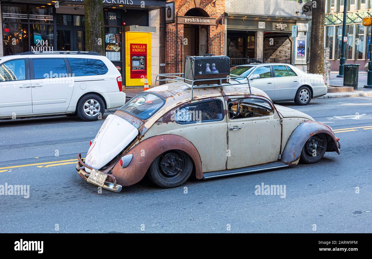 CHARLOTTE, NC, USA-26 JAN 2020: A rough-looking Volkswagen Beetle with a 1961 tag cruises down Tryon St. on a sunny winter Sunday. Stock Photo