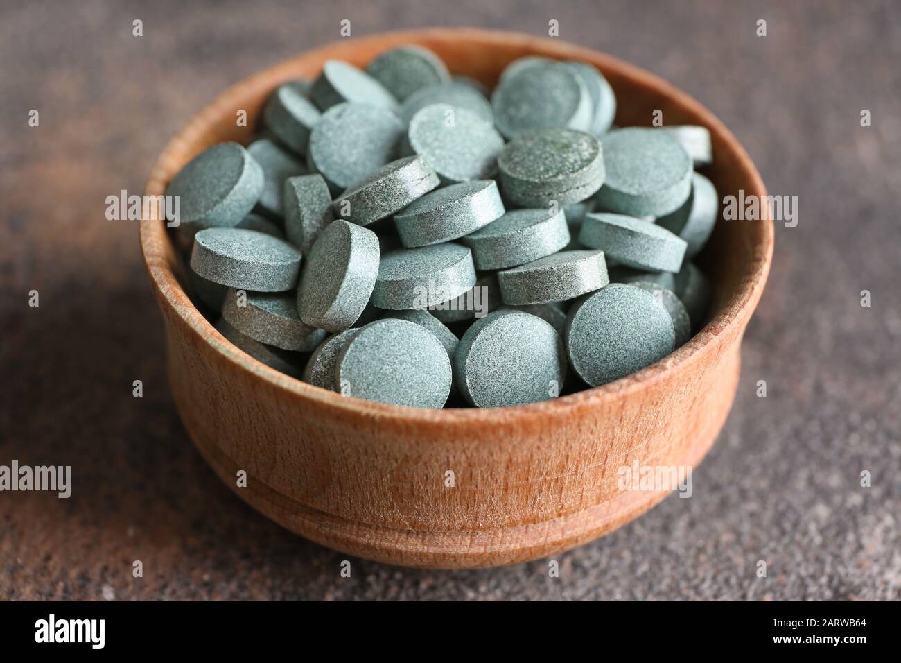 Bowl with spirulina pills on table Stock Photo