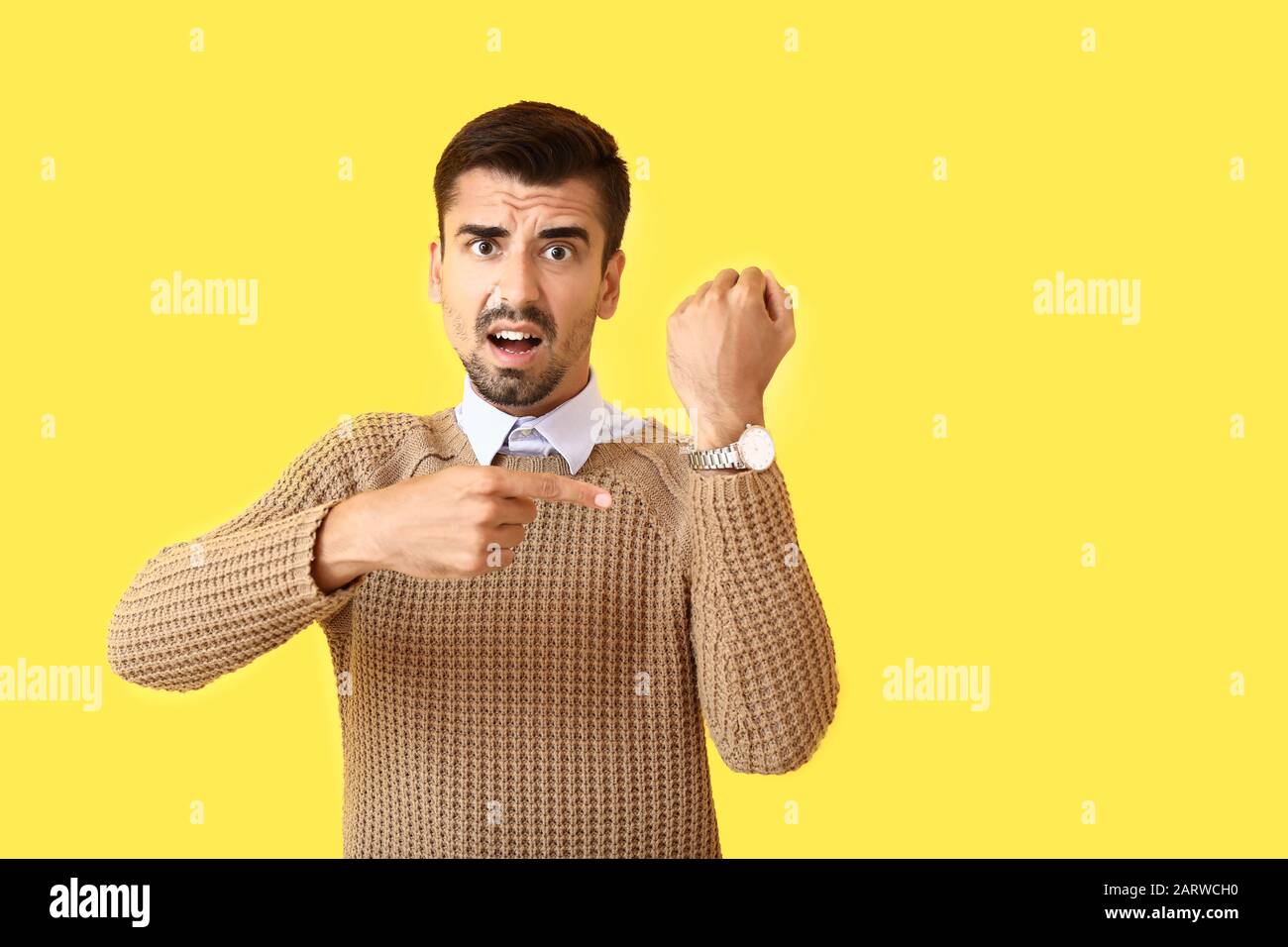 Stressed man pointing at his wrist watch on color background Stock Photo