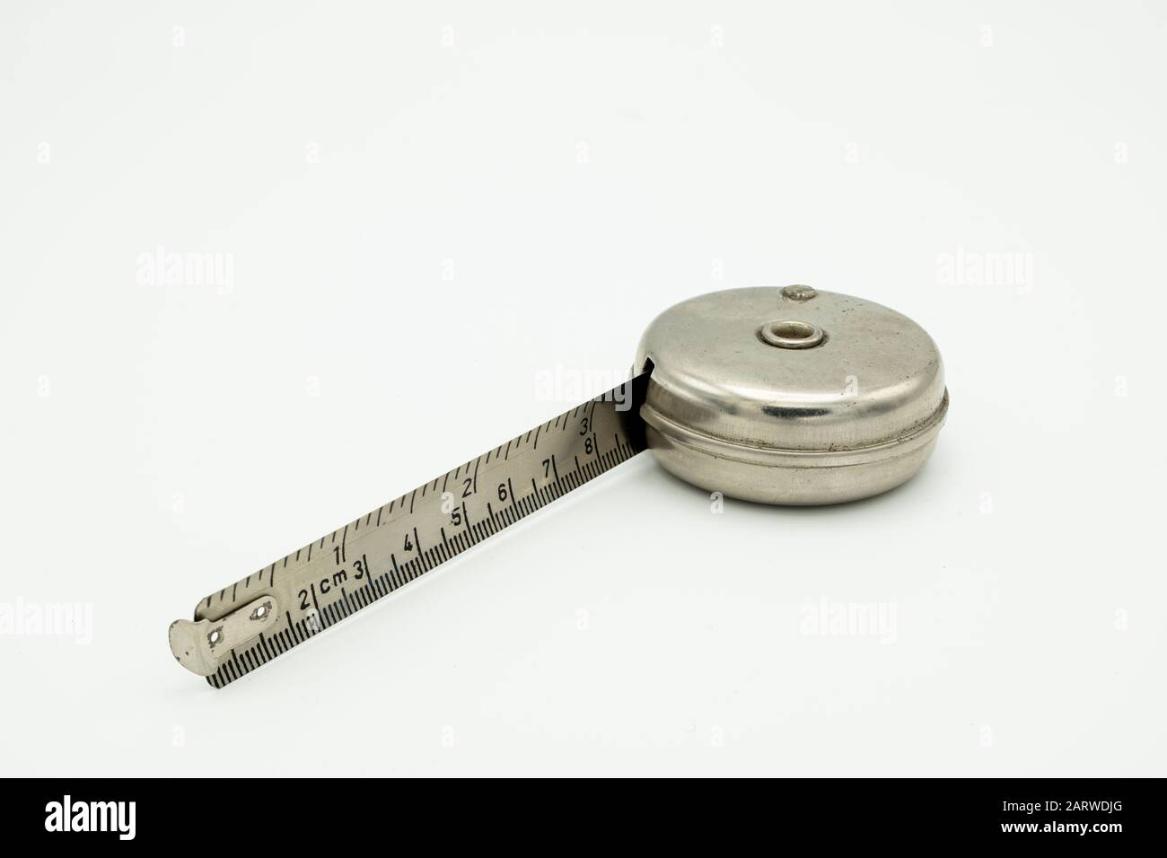 Closeup of an old measuring tape made of steel lying on a white