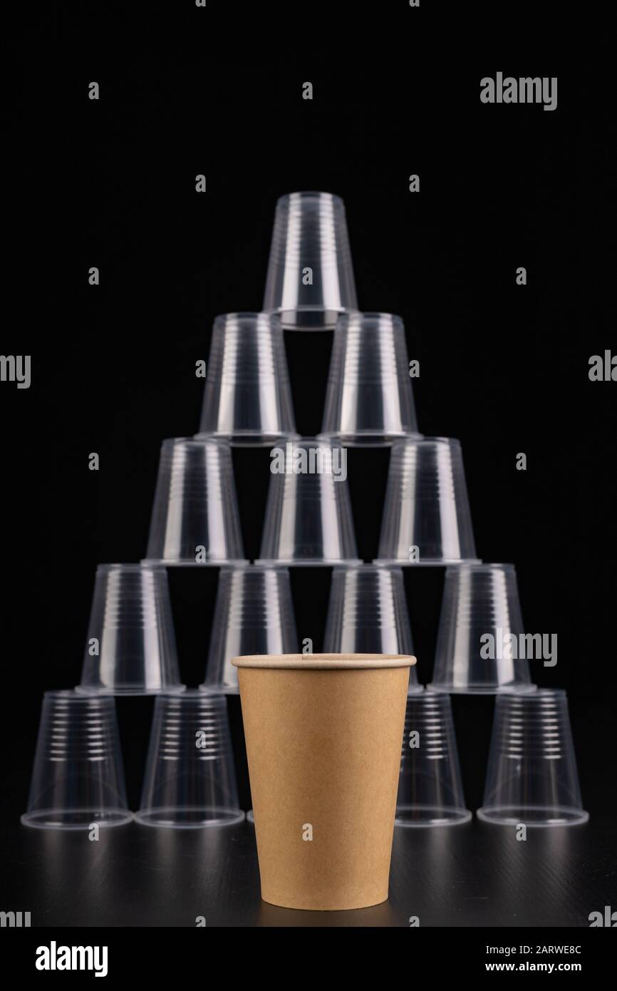 Plastic versus cardboard cups. Disposable tableware set on a table. Dark background. Stock Photo