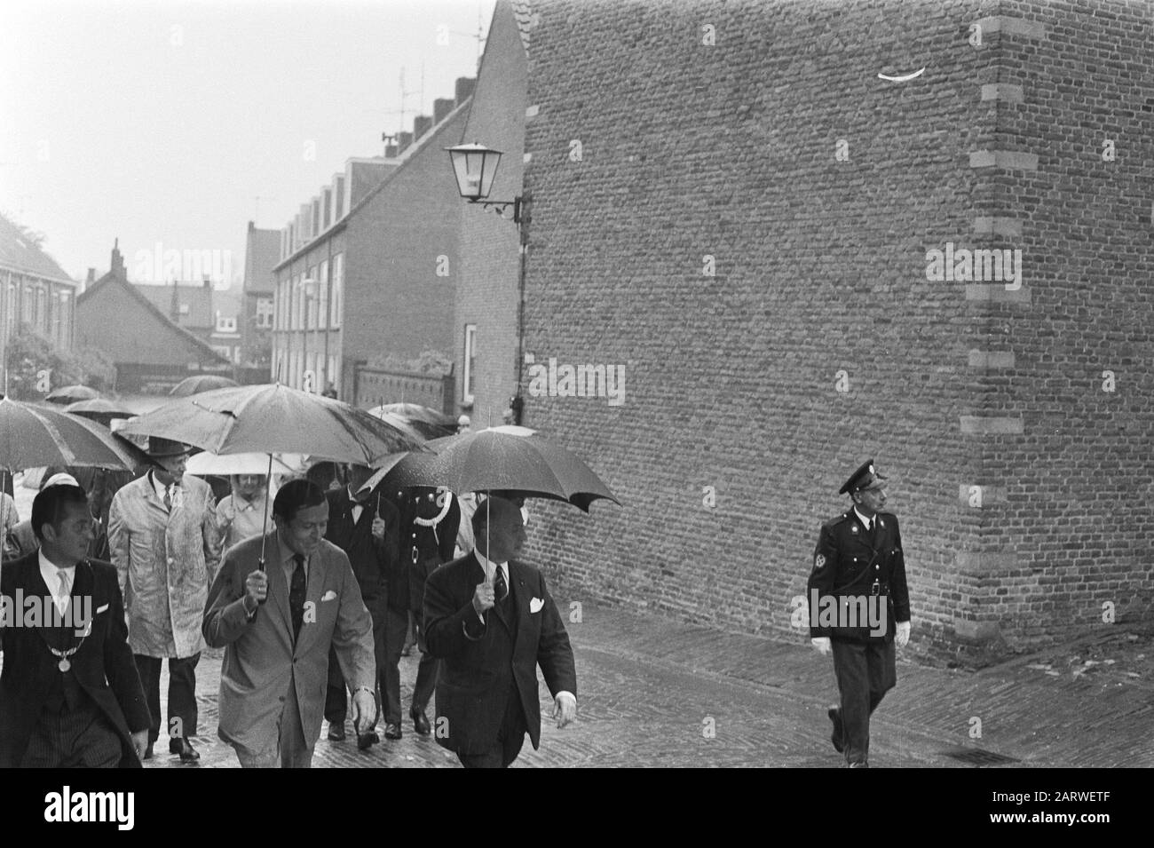 Prince Claus gives the start for Woudrichems Rehabilitation in Woudrichem  Vooraan prince Claus (l) and mayor Voster with umbrella Date: 14 May 1971 Location: Noord-Brabant, Woudrichem Keywords: mayors, umbrellas, princes, rain Personal name: Claus, prince, Voster, L.M. Institution name: Water gate Stock Photo