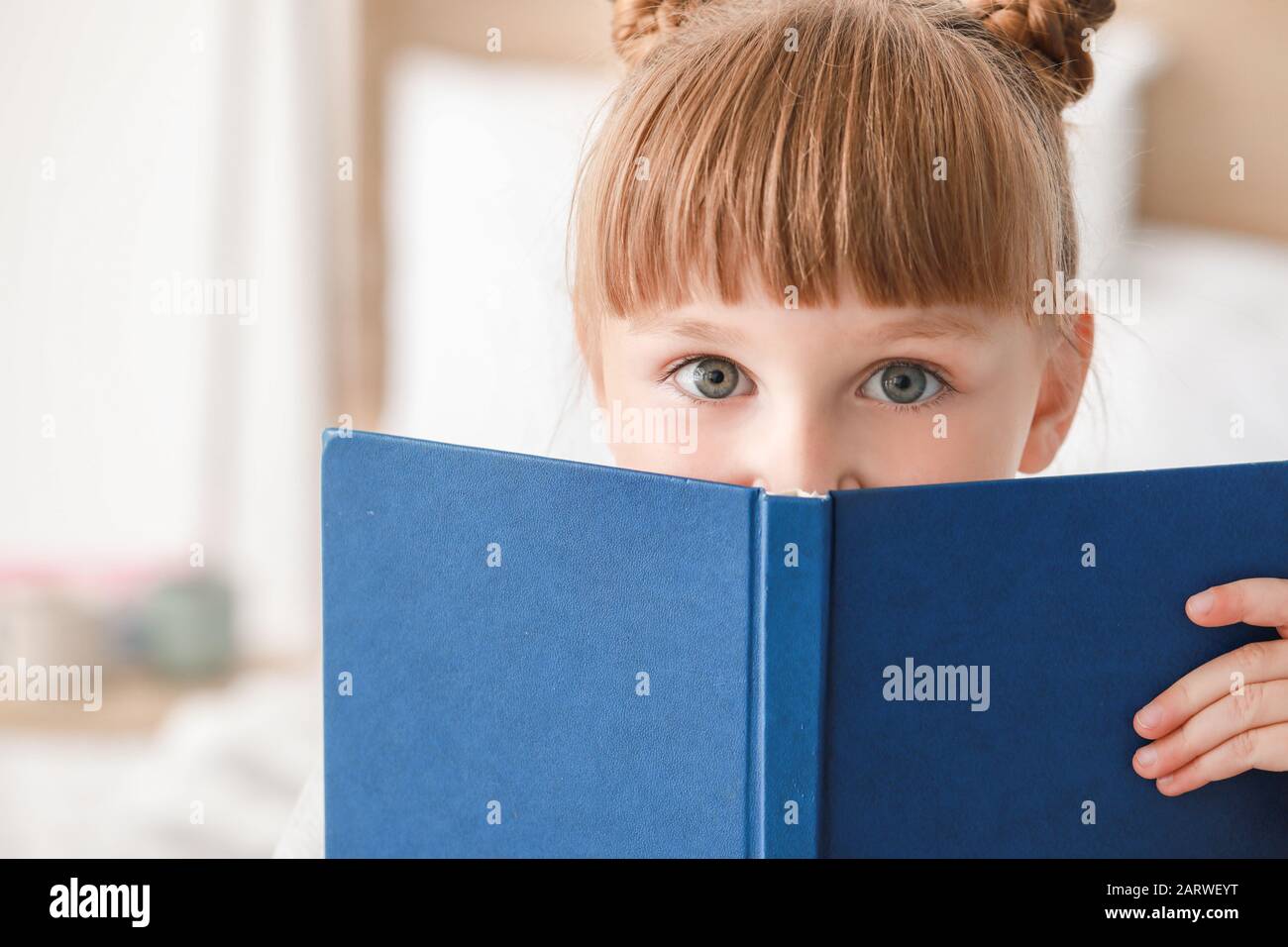 Cute little girl reading book at home Stock Photo - Alamy