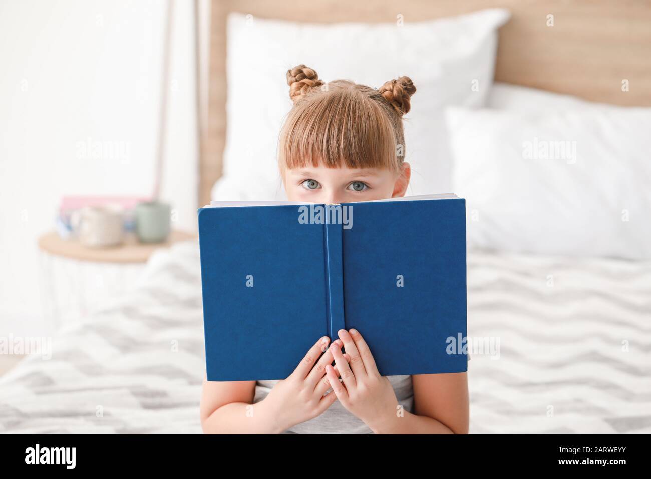 Cute little girl reading book at home Stock Photo - Alamy