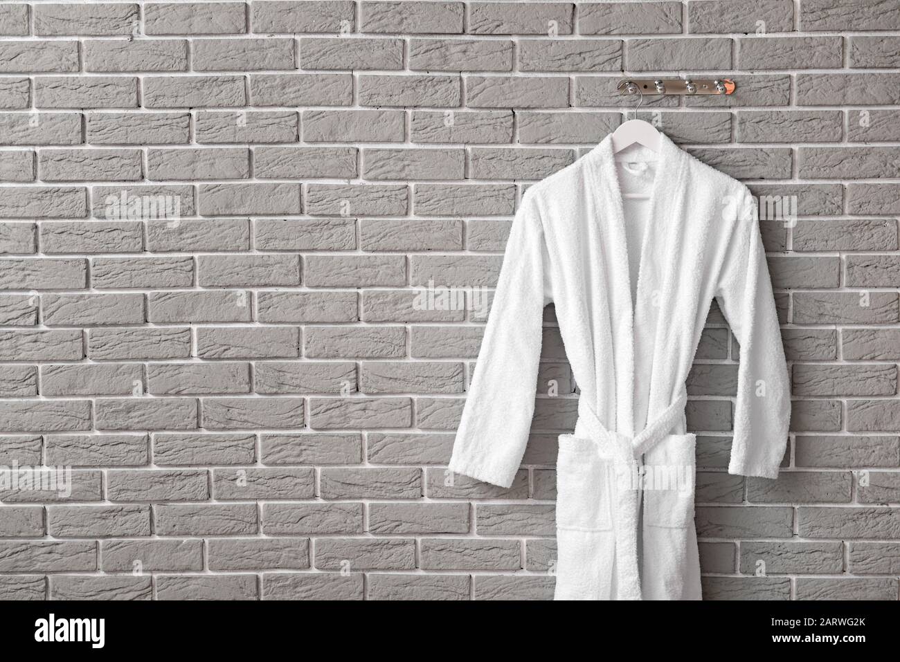 Clean bathrobe hanging on brick wall Stock Photo Alamy