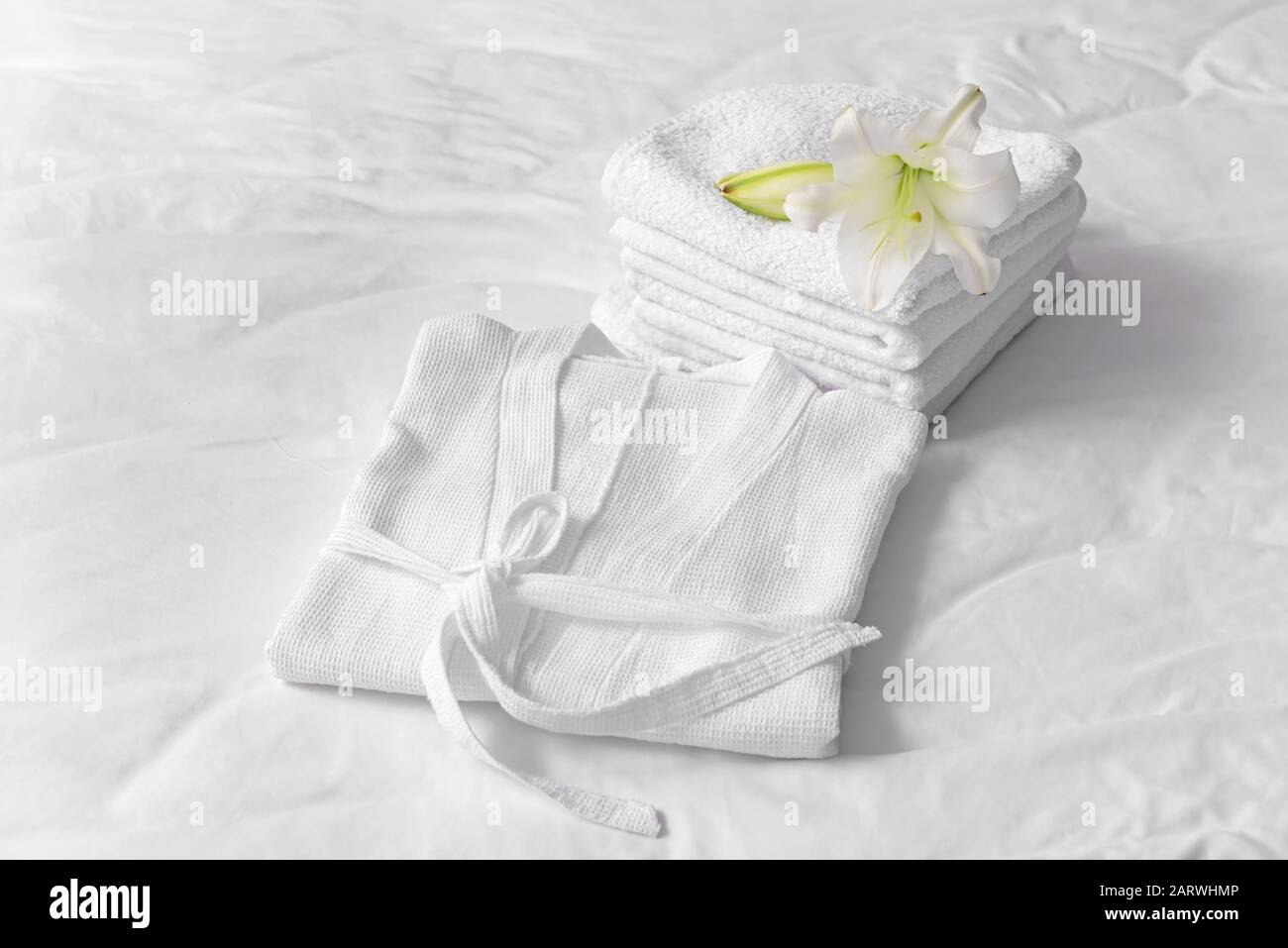 Soft clean bathrobe and towels on bed Stock Photo