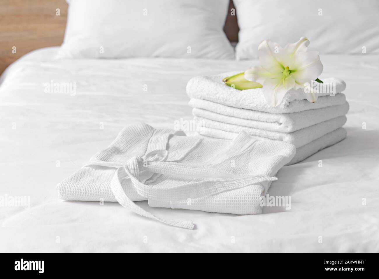 Soft clean bathrobe and towels on bed Stock Photo