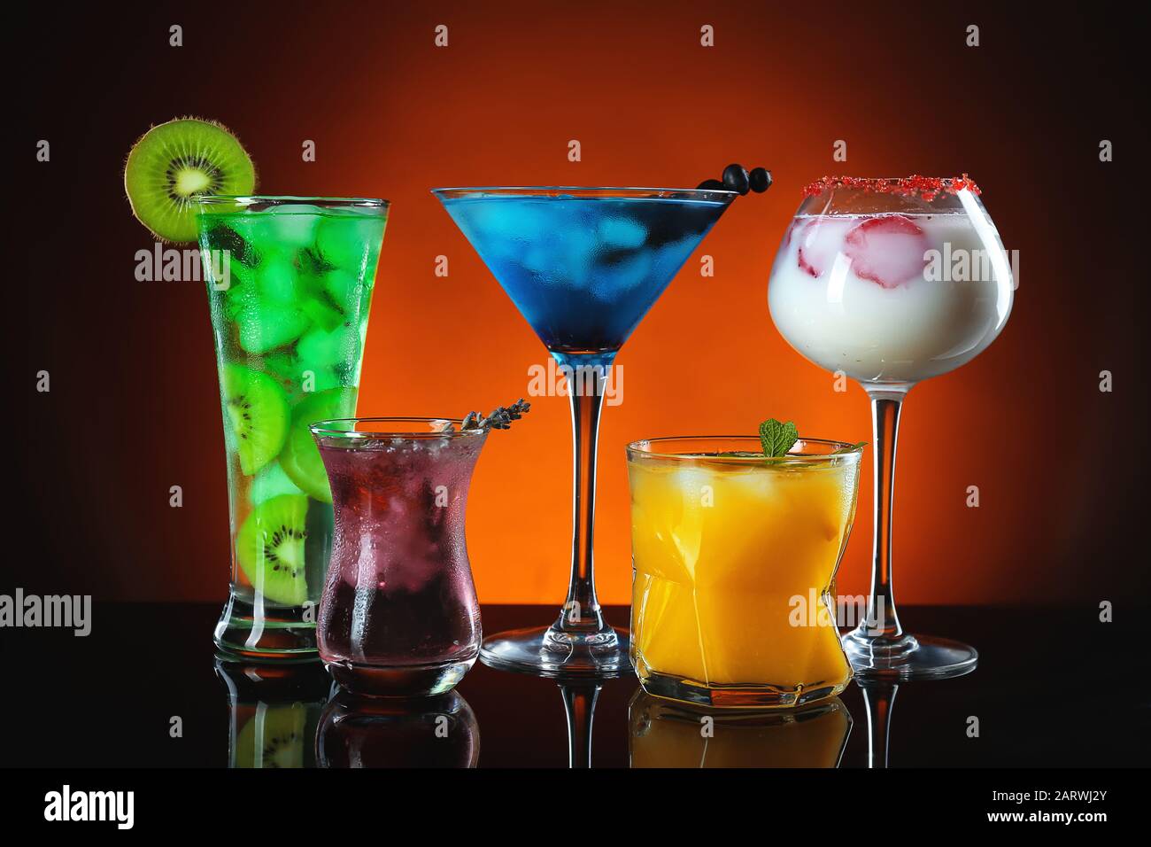 Different tasty cocktails on dark color background Stock Photo - Alamy