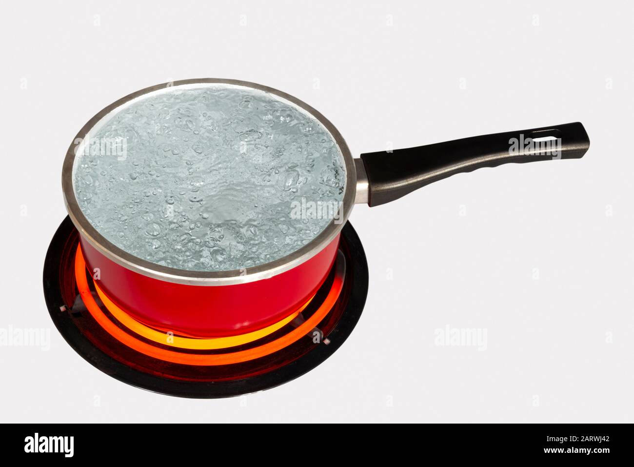 Horizontal shot looking down on a red pot of boiling water on top of a stove with the burner turned to high.  White background.  Copy space. Stock Photo