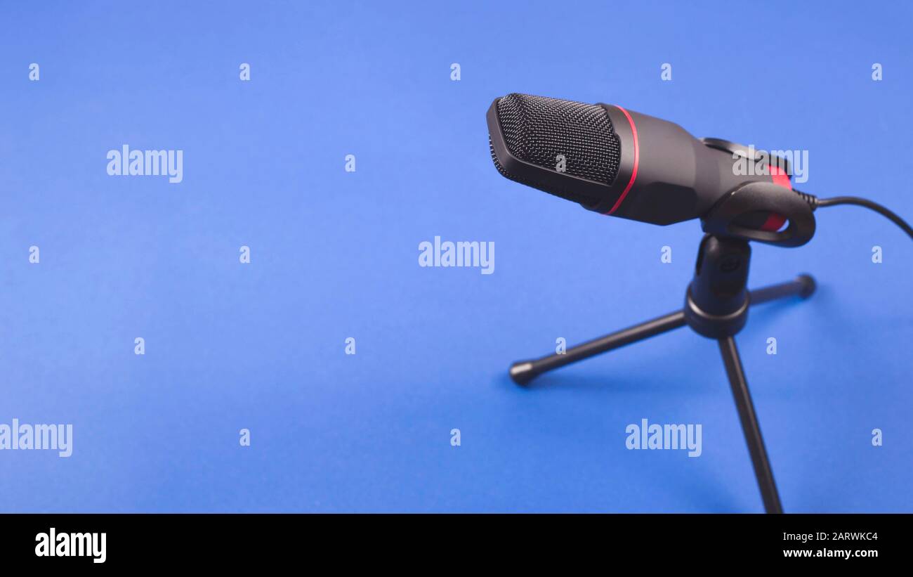 A microphone for creating professional sound and podcast production. On a blue background with opy space. Stock Photo