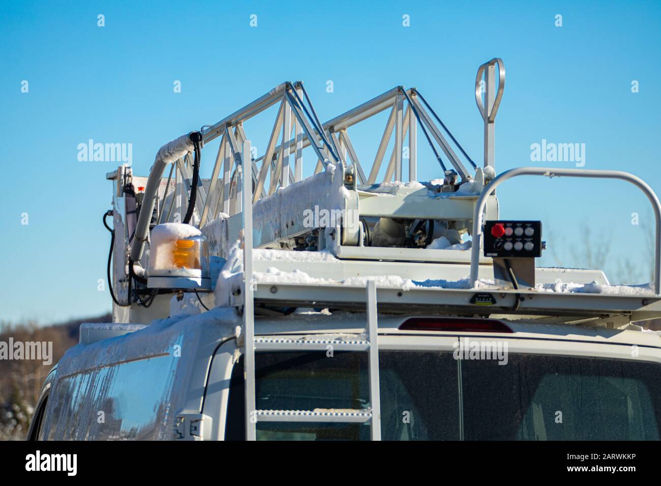 A close up and detailed view of the operating equipment atop a mobile works van, amber light and scissor lift on bucket truck. Under a blue winter sky Stock Photo