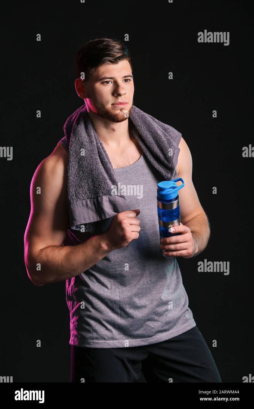 Sporty young man with bottle of water on dark background Stock Photo ...