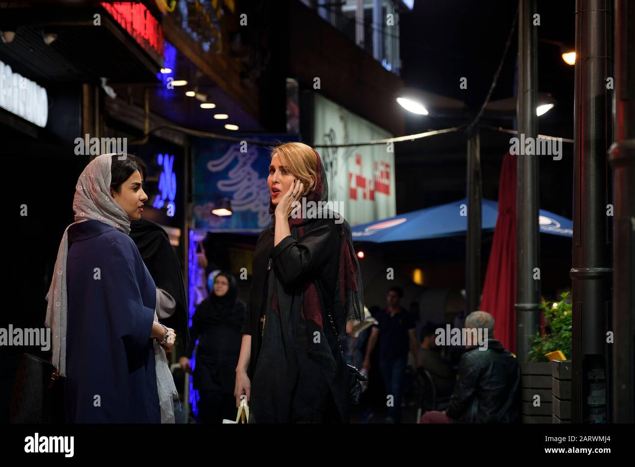 Persian girls are spending their free time on the streets of Tehran. Young Iranian boys and girls usually visit their friends in front of a cafe. Stock Photo