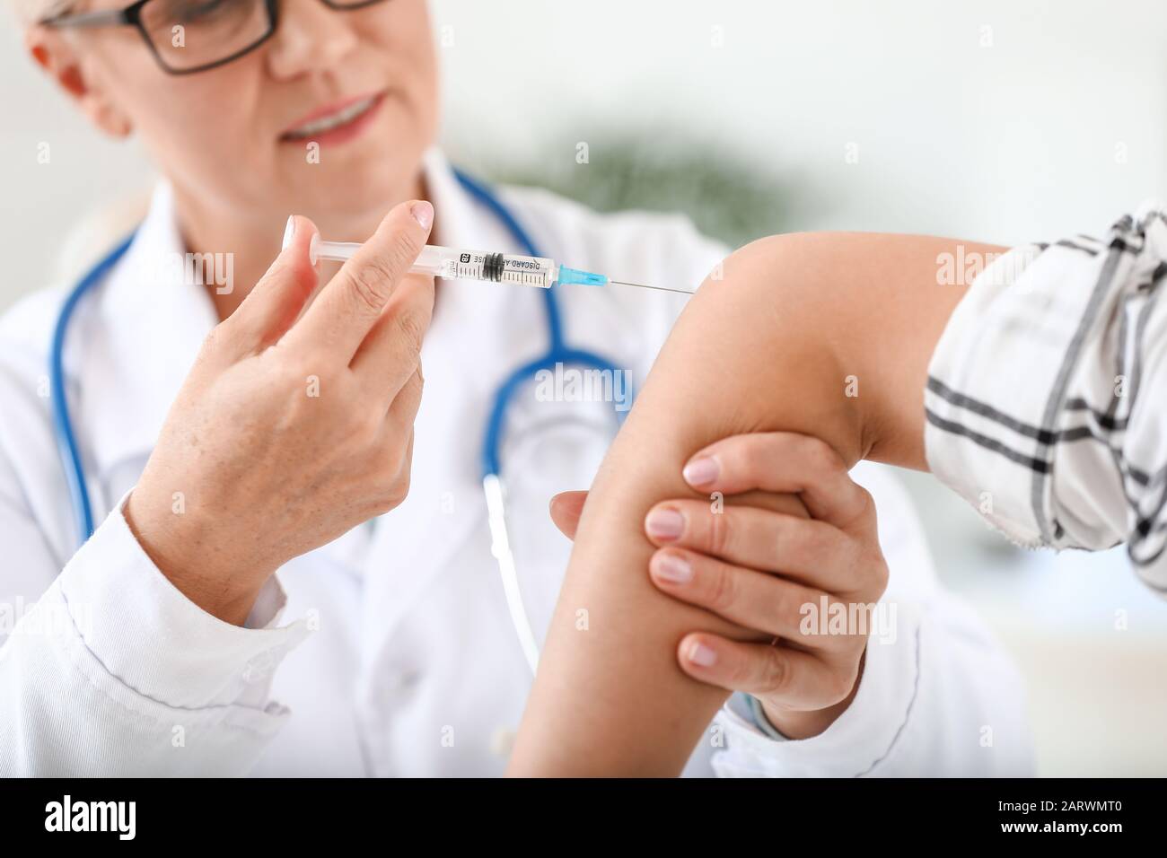 Mature doctor giving young woman with joint pain injection in clinic ...