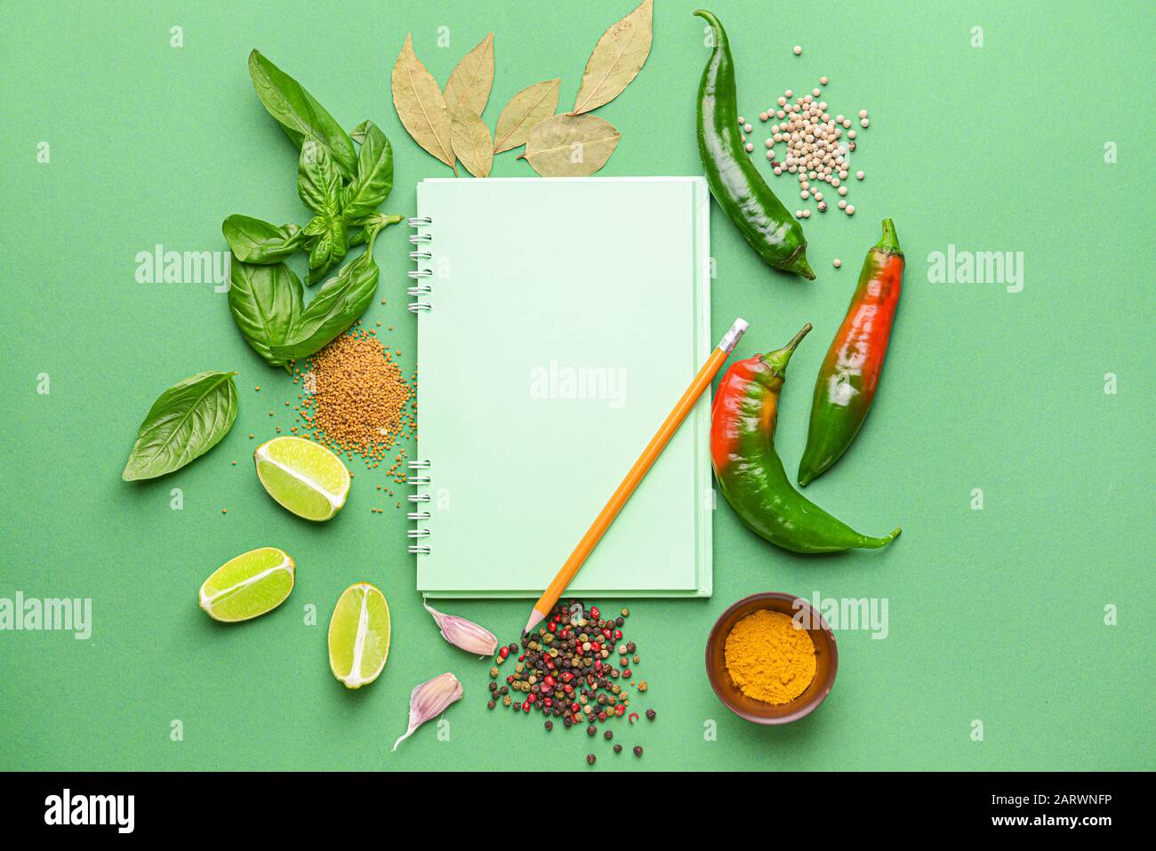 Empty notebook with different spices on color background Stock Photo