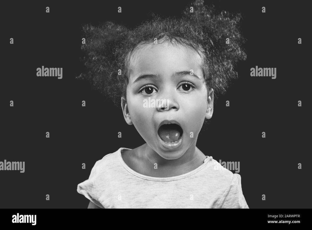Black and white portrait of little African-American girl on dark background Stock Photo