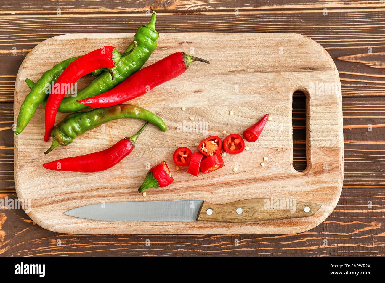 Hot chili peppers and knife on wooden cutting board Stock Photo - Alamy
