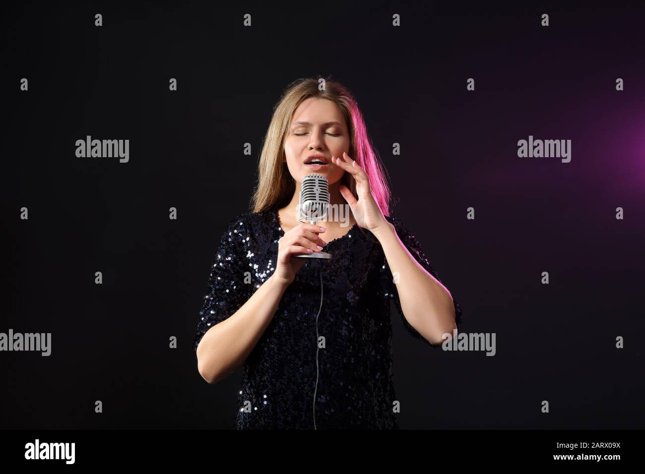 Beautiful young female singer with microphone on stage Stock Photo Alamy