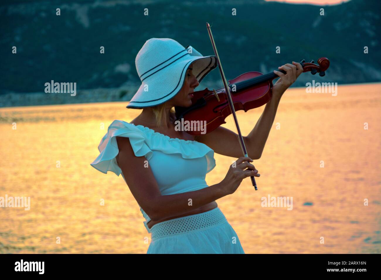 Beautiful woman playing violin at the sea with sunset background Stock ...