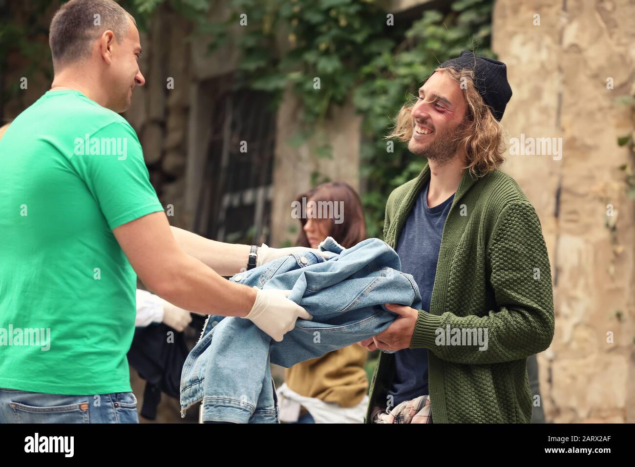 Volunteers giving clothes to homeless people outdoors Stock Photo