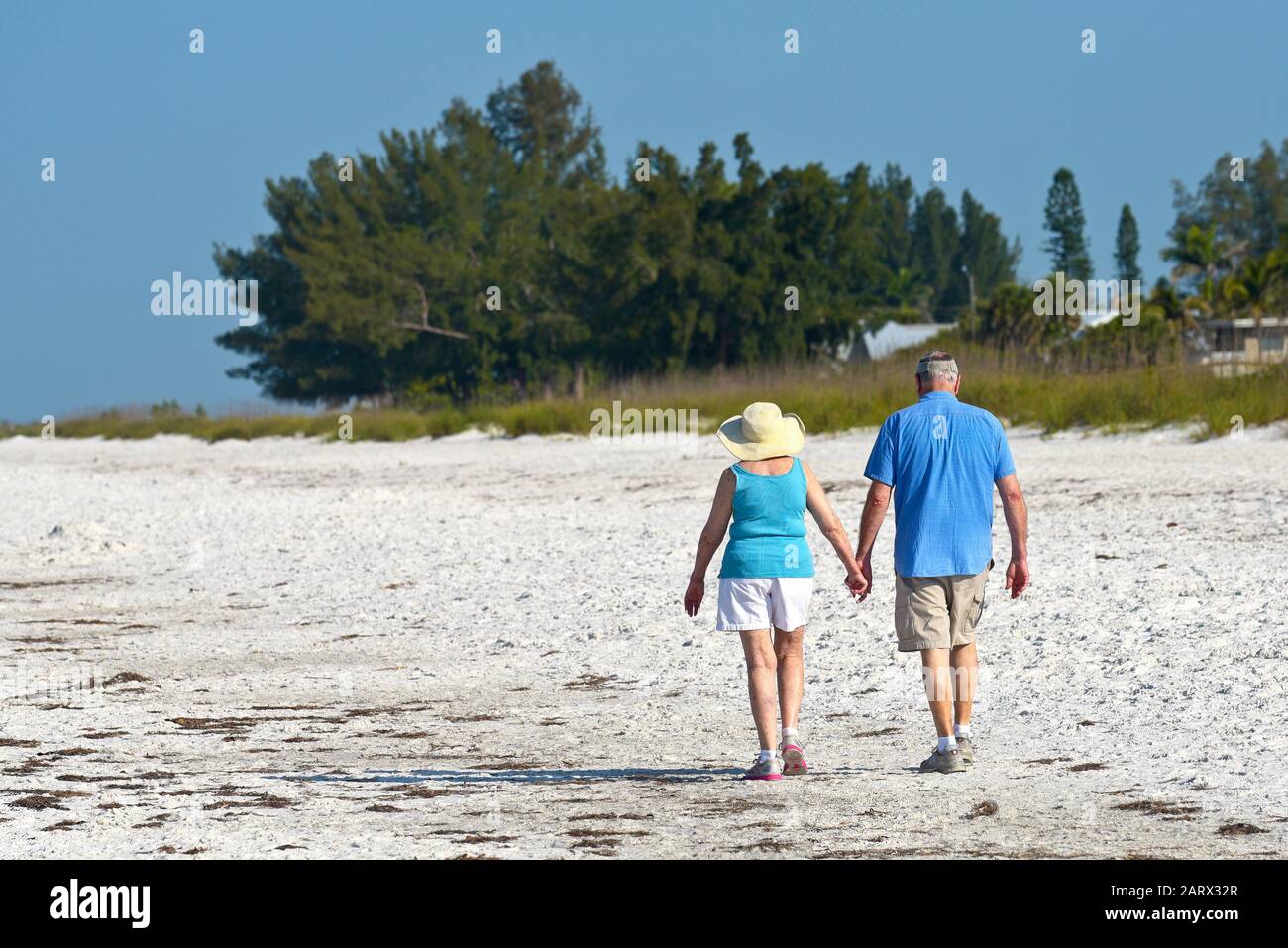 HOLMES BEACH, ANNA MARIA ISLAND, FL / USA - May 1, 2018: Senior Couple holding hands while taking an early morning walk on the beach. Stock Photo