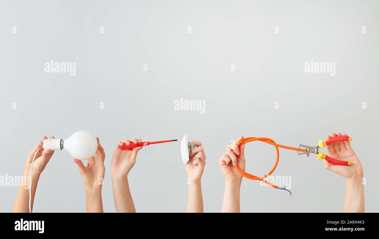 Female hands with electrician's tools on light background Stock Photo