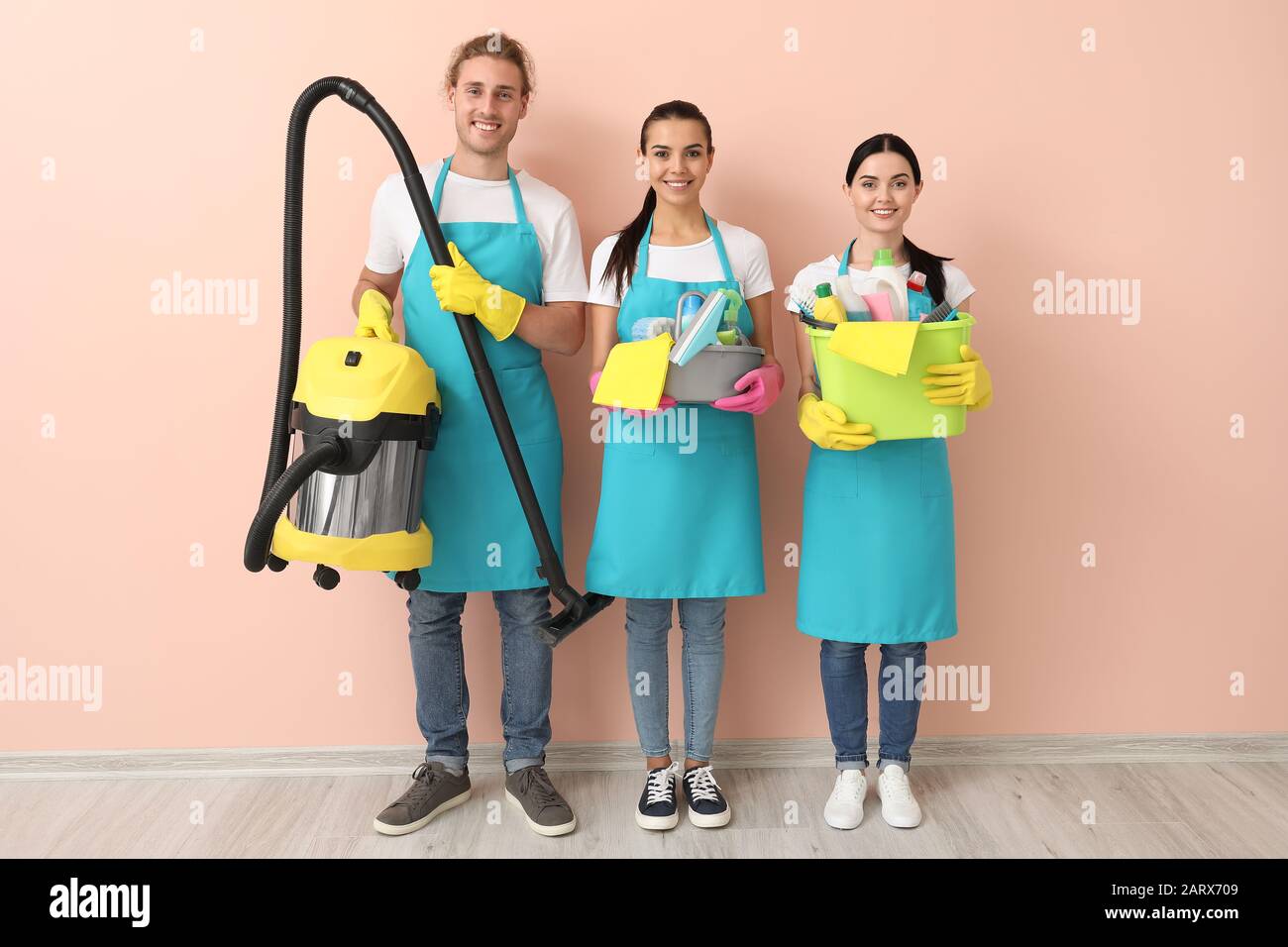 Team of janitors with cleaning supplies near color wall Stock Photo
