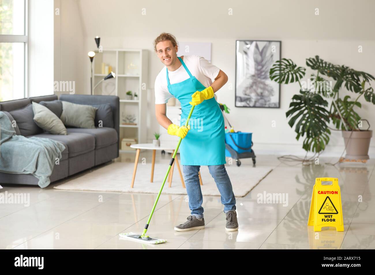 Male janitor mopping floor in flat Stock Photo