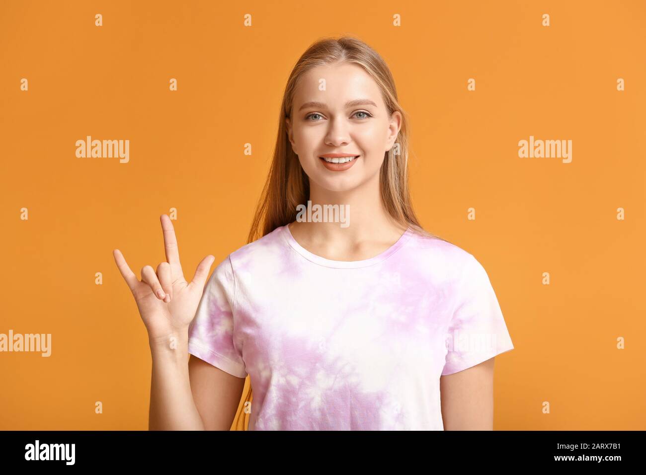 Young deaf mute woman using sign language on color background Stock Photo