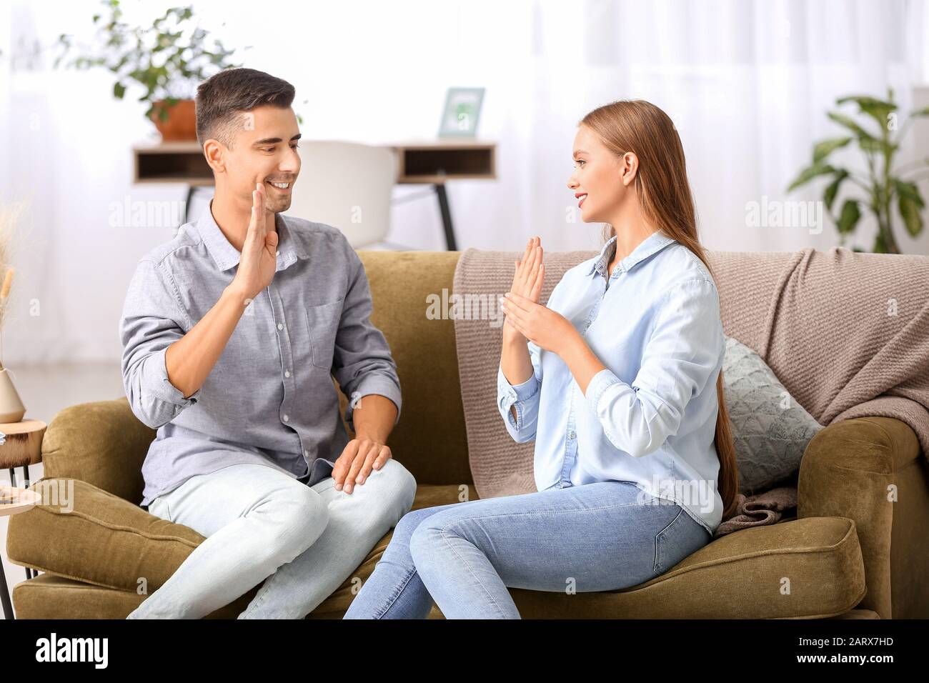 Young deaf mute couple using sign language at home Stock Photo