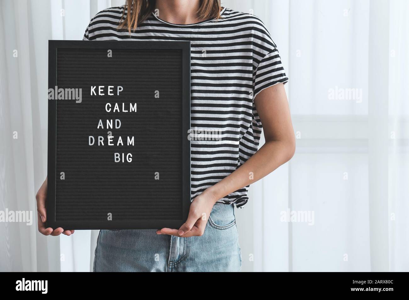 Woman holding board with motivation phrase indoors Stock Photo