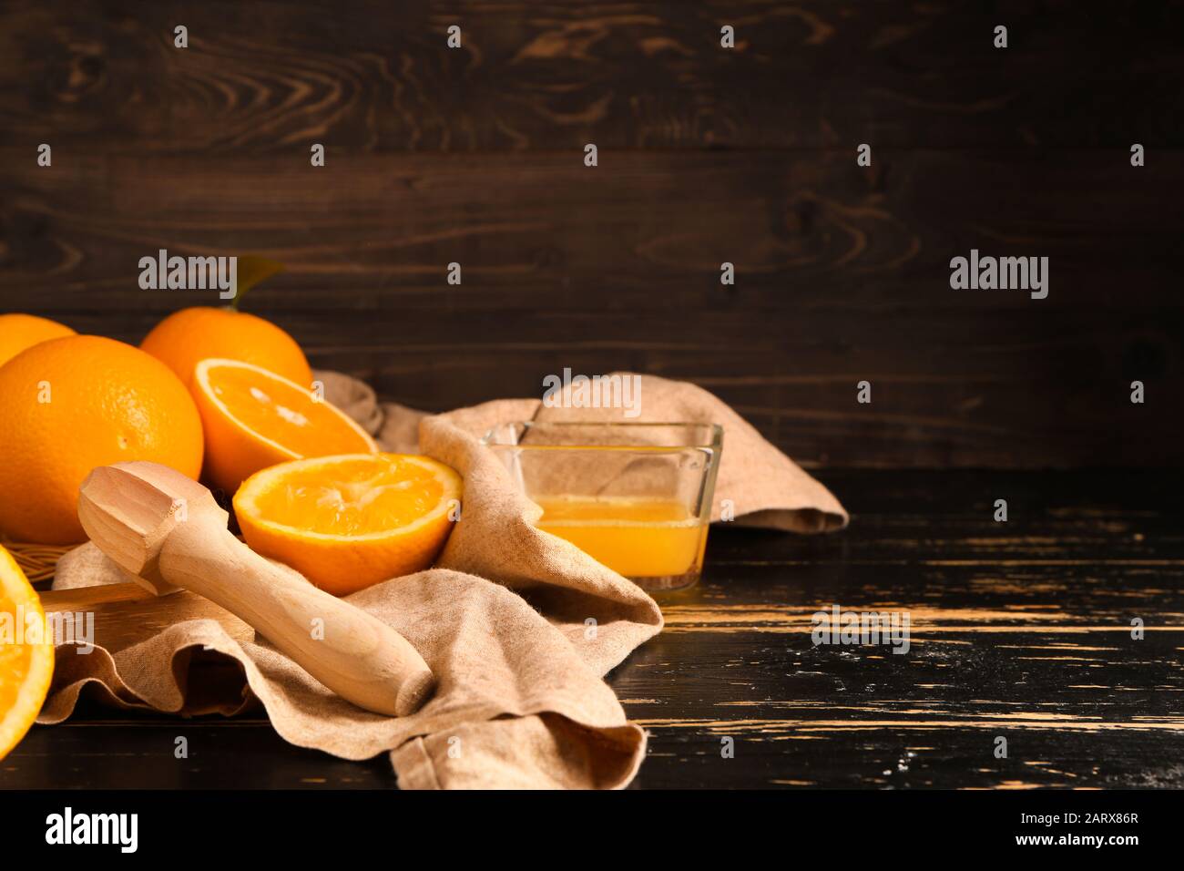 Squeezer with fresh oranges and juice on dark table Stock Photo