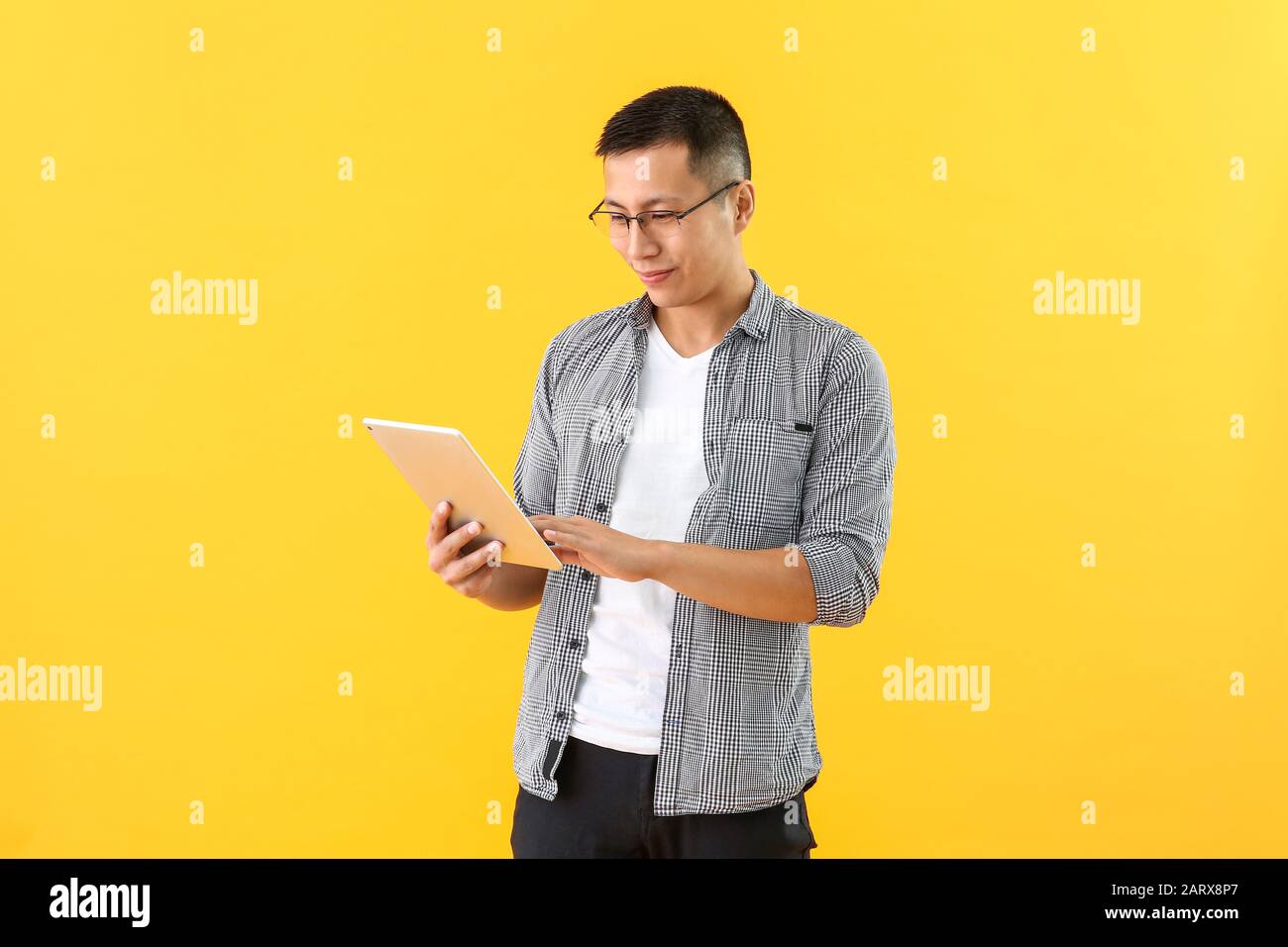 Male Asian programmer with tablet computer on color background Stock Photo