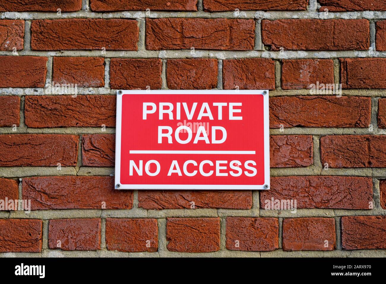 A red private road no access sign on a brick wall Stock Photo