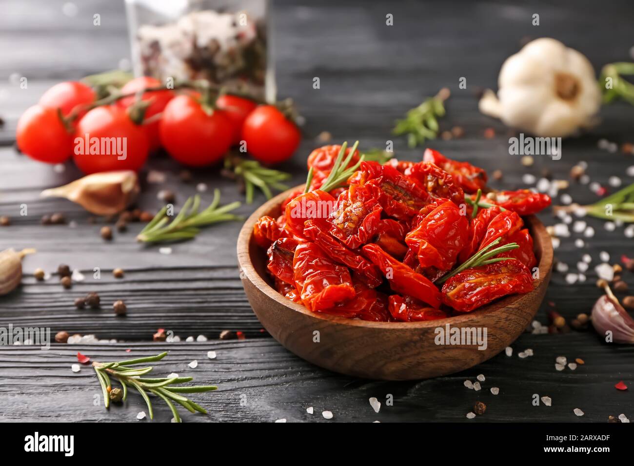 Plate with dried tomatoes and spices on wooden table Stock Photo