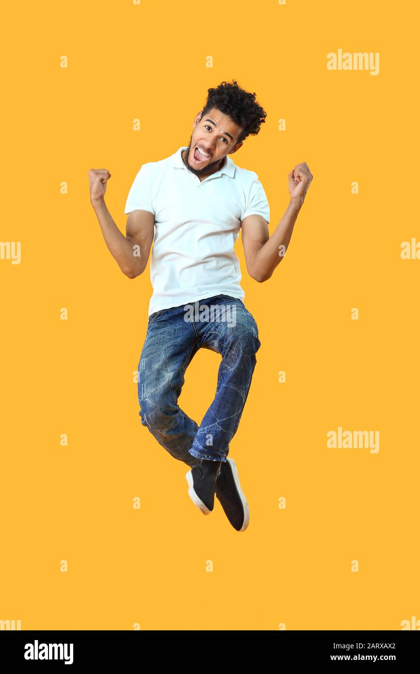 Portrait of jumping African-American man on color background Stock Photo