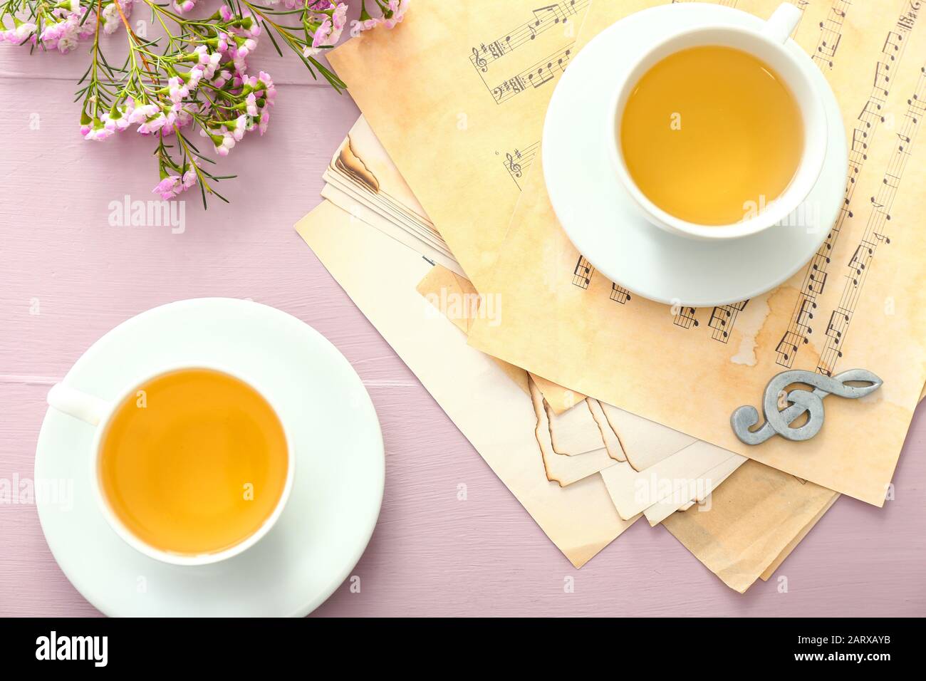 Cups of hot tea with music sheets on table Stock Photo