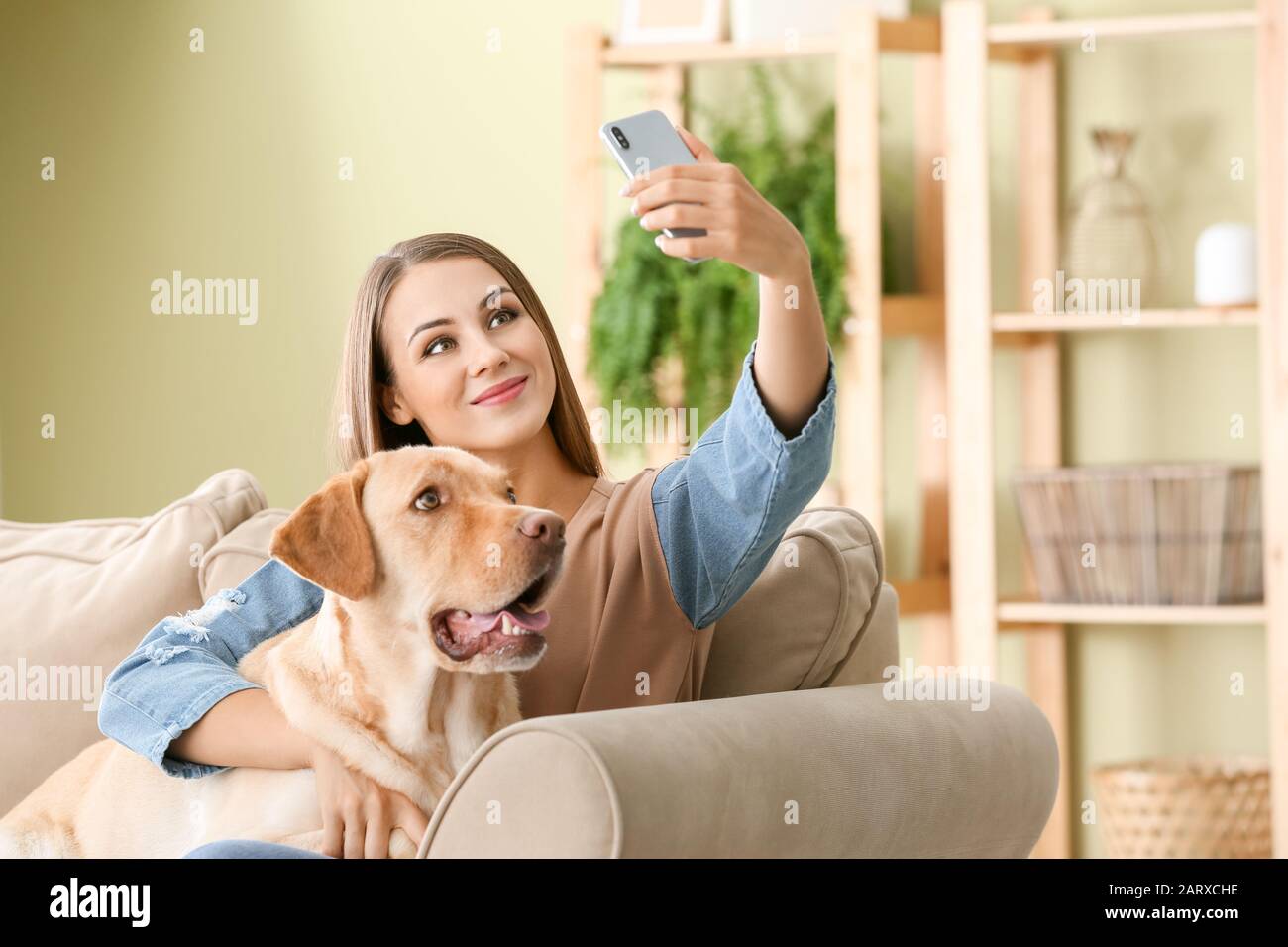 Beautiful young woman with cute dog taking selfie at home Stock Photo ...