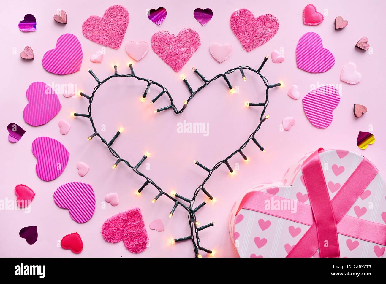 Heart made of glowing garland and gift on color background Stock Photo -  Alamy